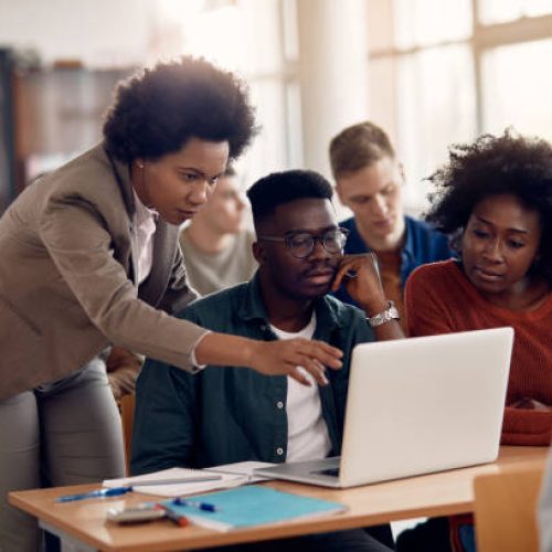 African American professor and her students using laptop during lecture in the classroom.